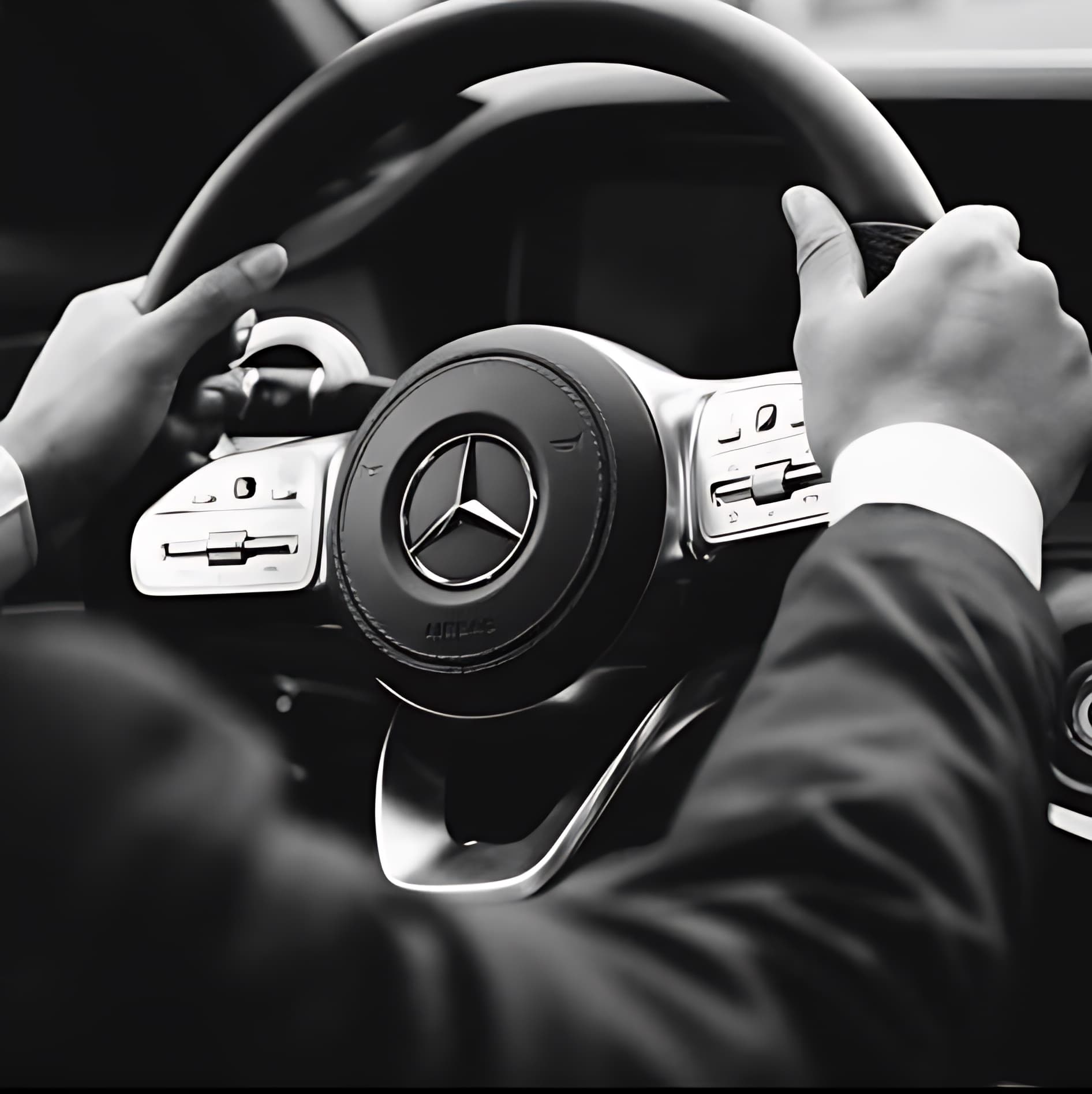 A suited driver at the wheel of a Mercedes